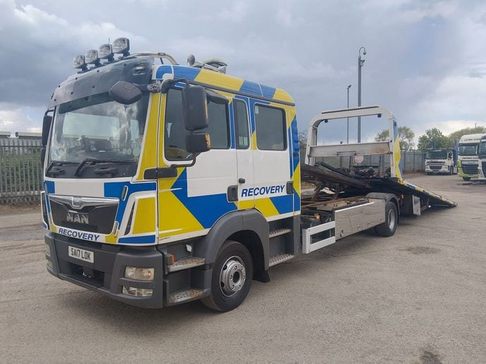 A MAN recovery truck in blue and yellow livery, with a slide bed on the back